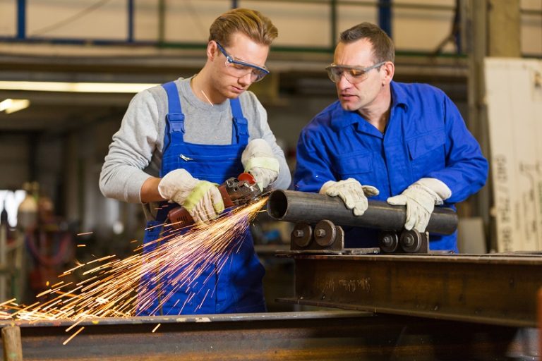 instructor teaches trainee how to use an angle grinder